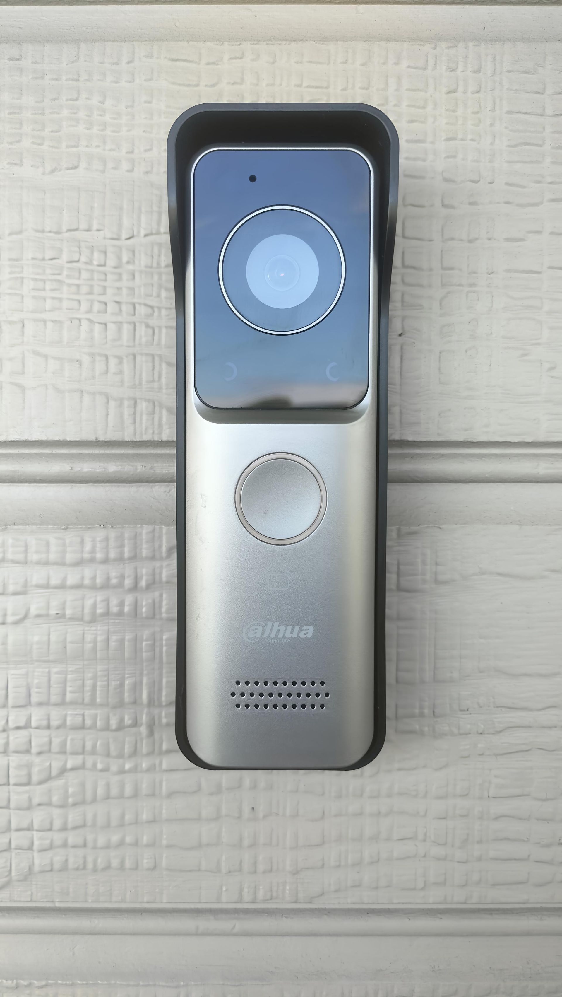 Silver and black video doorbell mounted on a white paneled door.