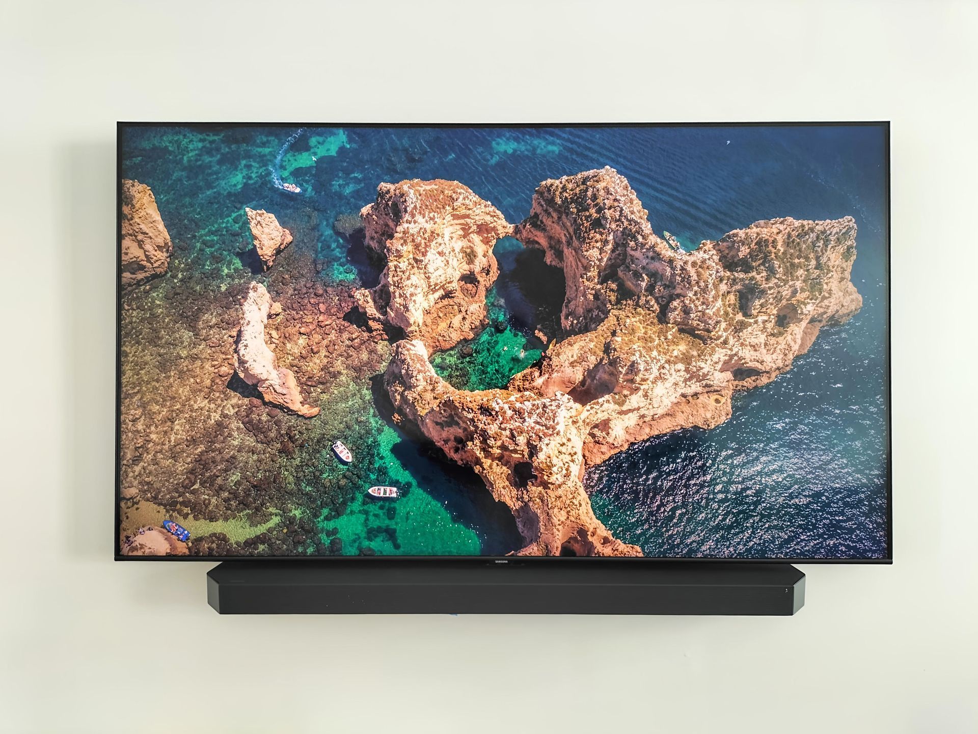 TV on a wall mount with tv playing and a brown cabinet underneath— Coastline Installations In Emu Park, QLD