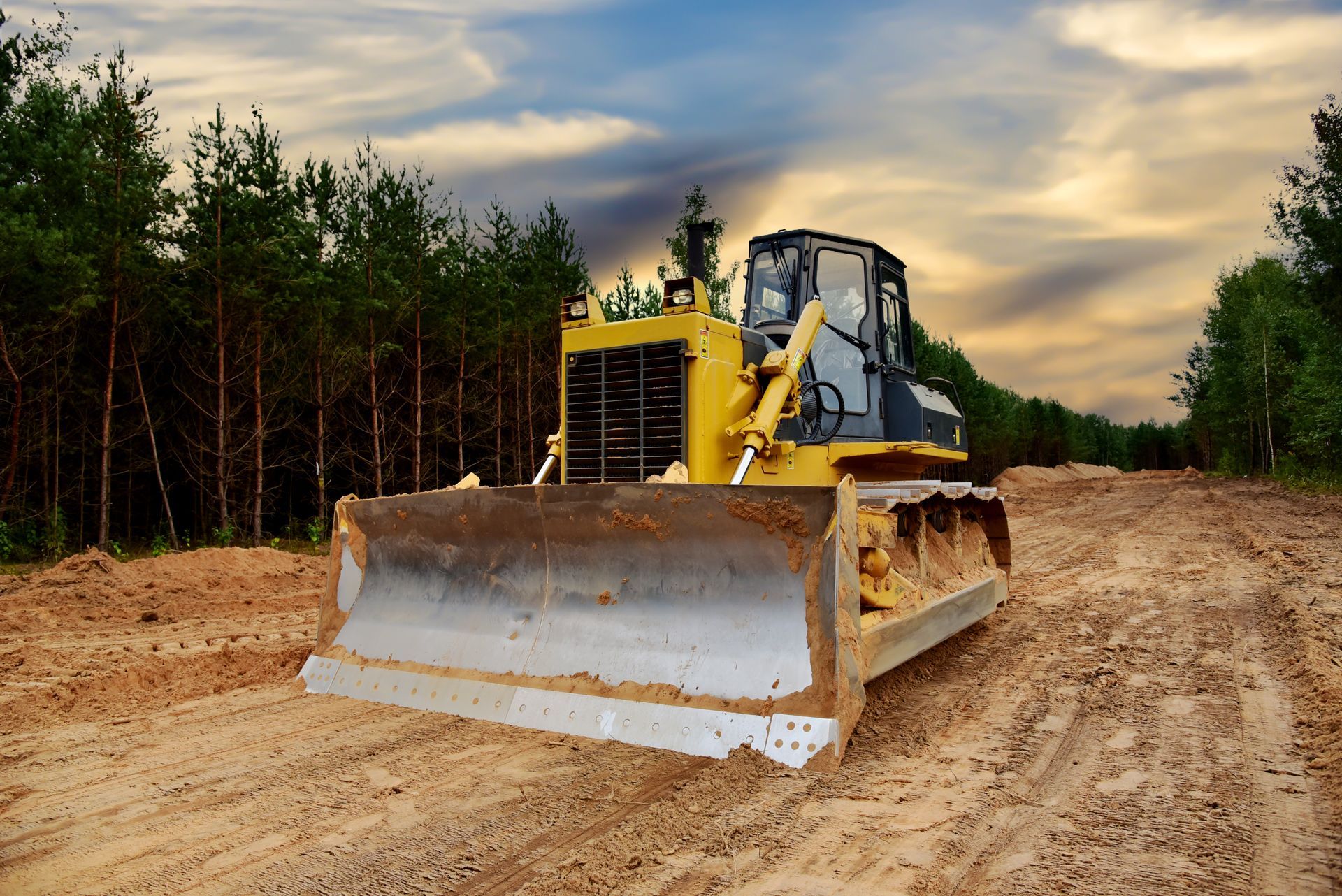 Dozer during clearing forest for construction new road. Bulldozer at forestry work on sunset background. Earth-moving equipment at road work, land clearing, grading, pool excavation, utility trenching.