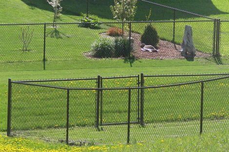 A chain link fence surrounds a lush green field.