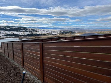 A wooden fence with a view of a lake and mountains in the background.