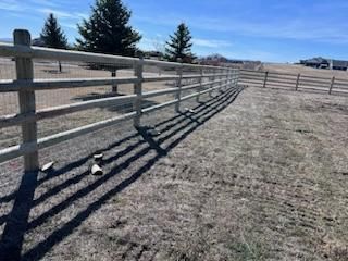 A wooden fence surrounds a dry grass field.