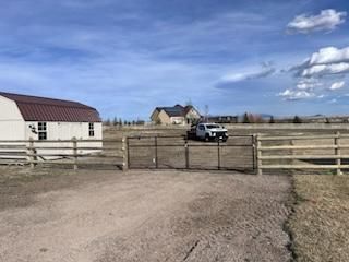 A white truck is parked in front of a barn behind a wooden fence.