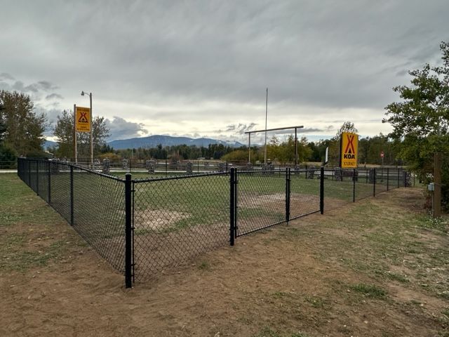 A chain link fence surrounds a field with a sign that says no dogs
