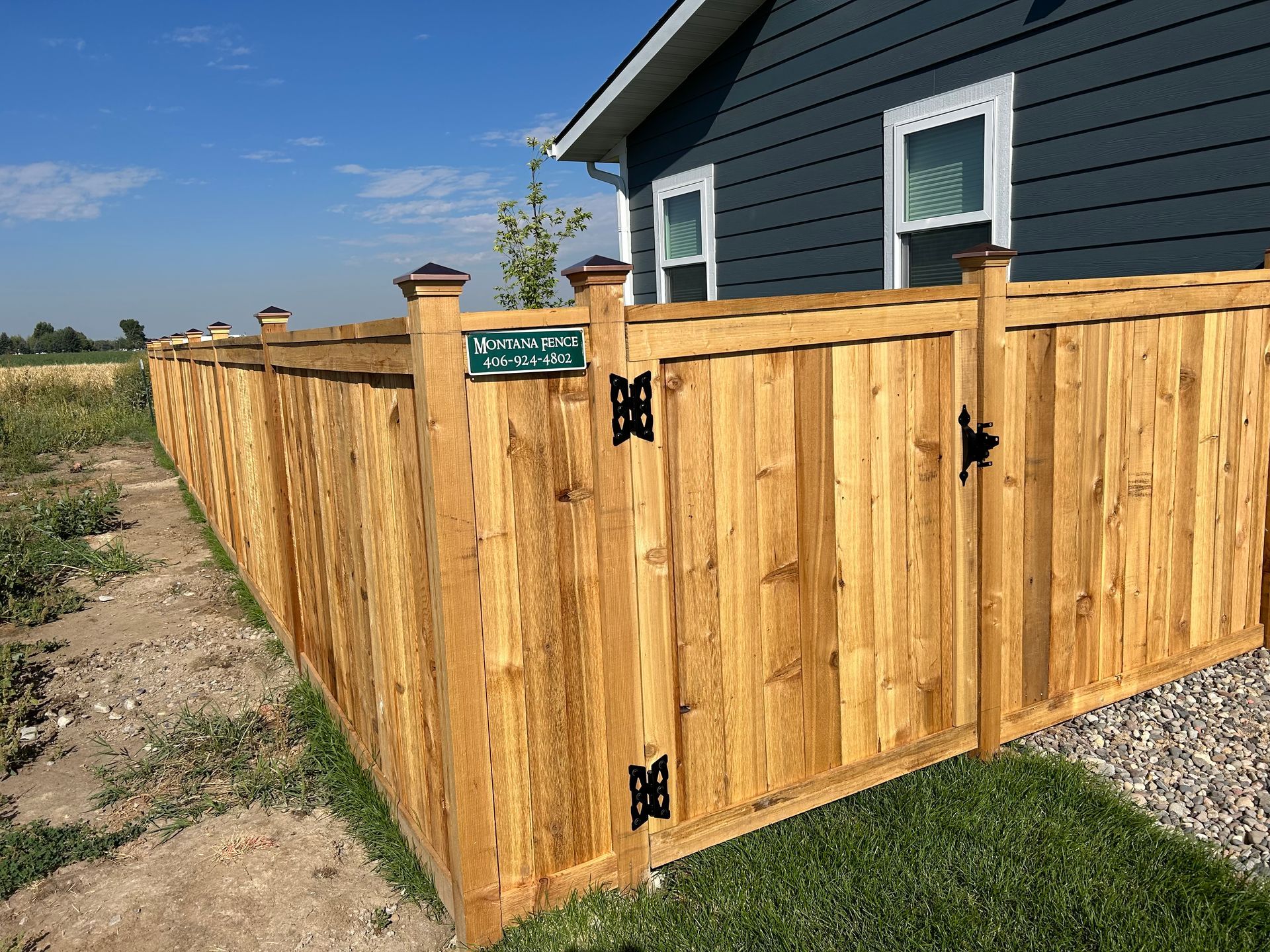 A wooden fence with a gate in front of a house.