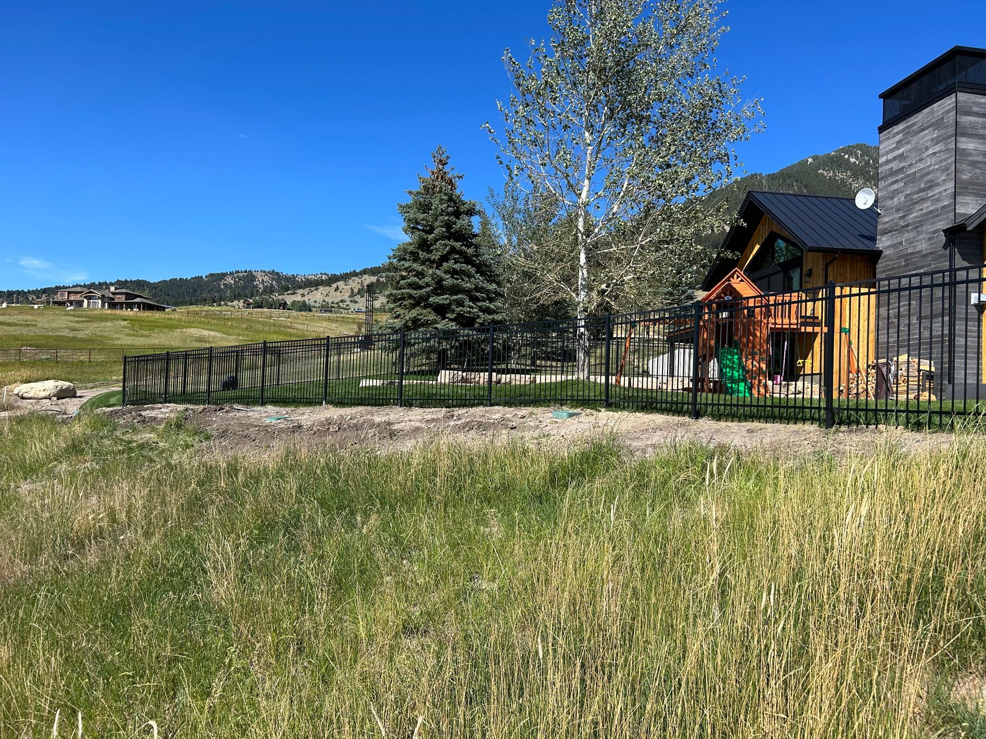 There is a house in the background and a fence in the foreground.
