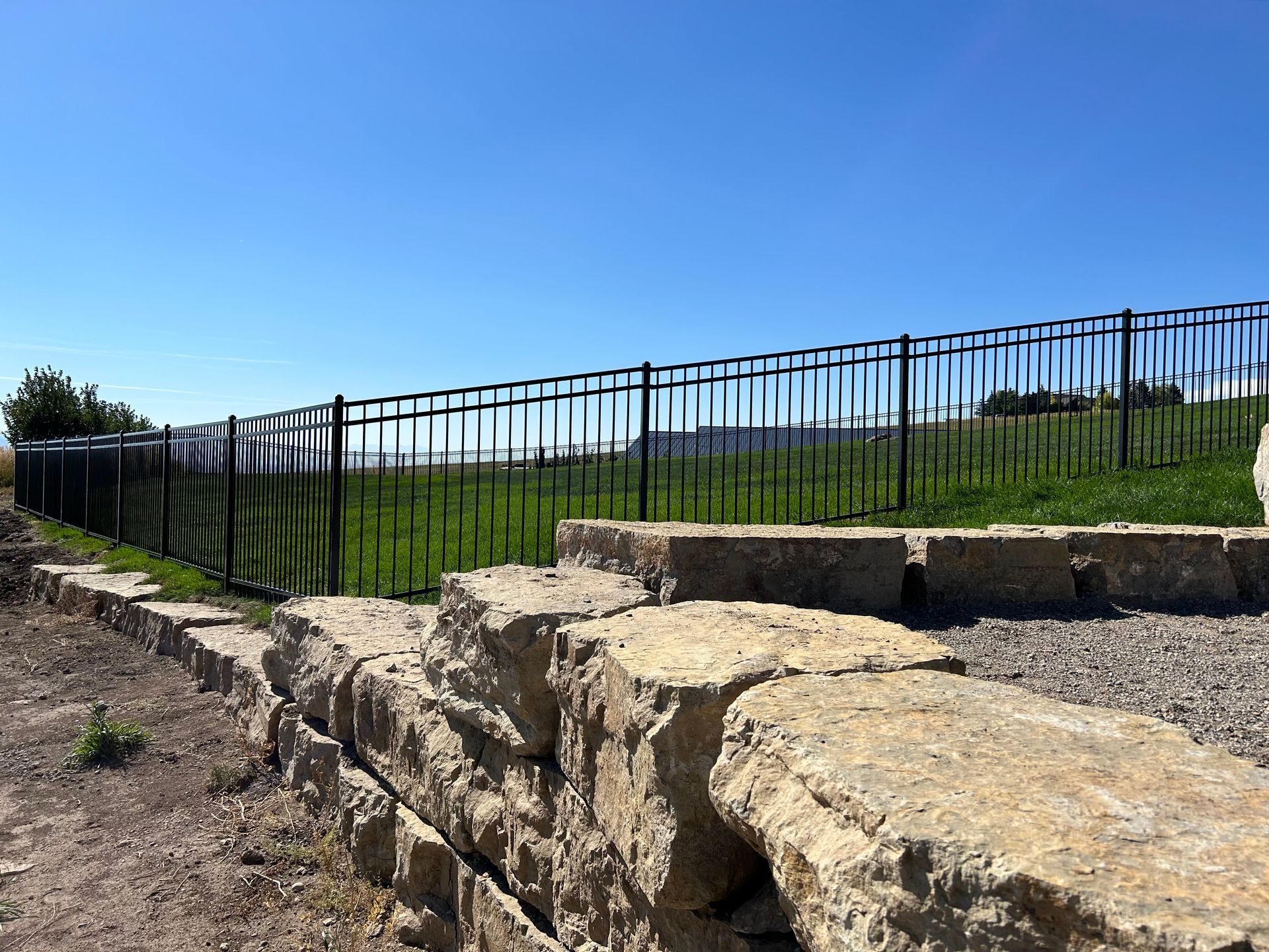 A stone wall with a metal fence surrounding it.