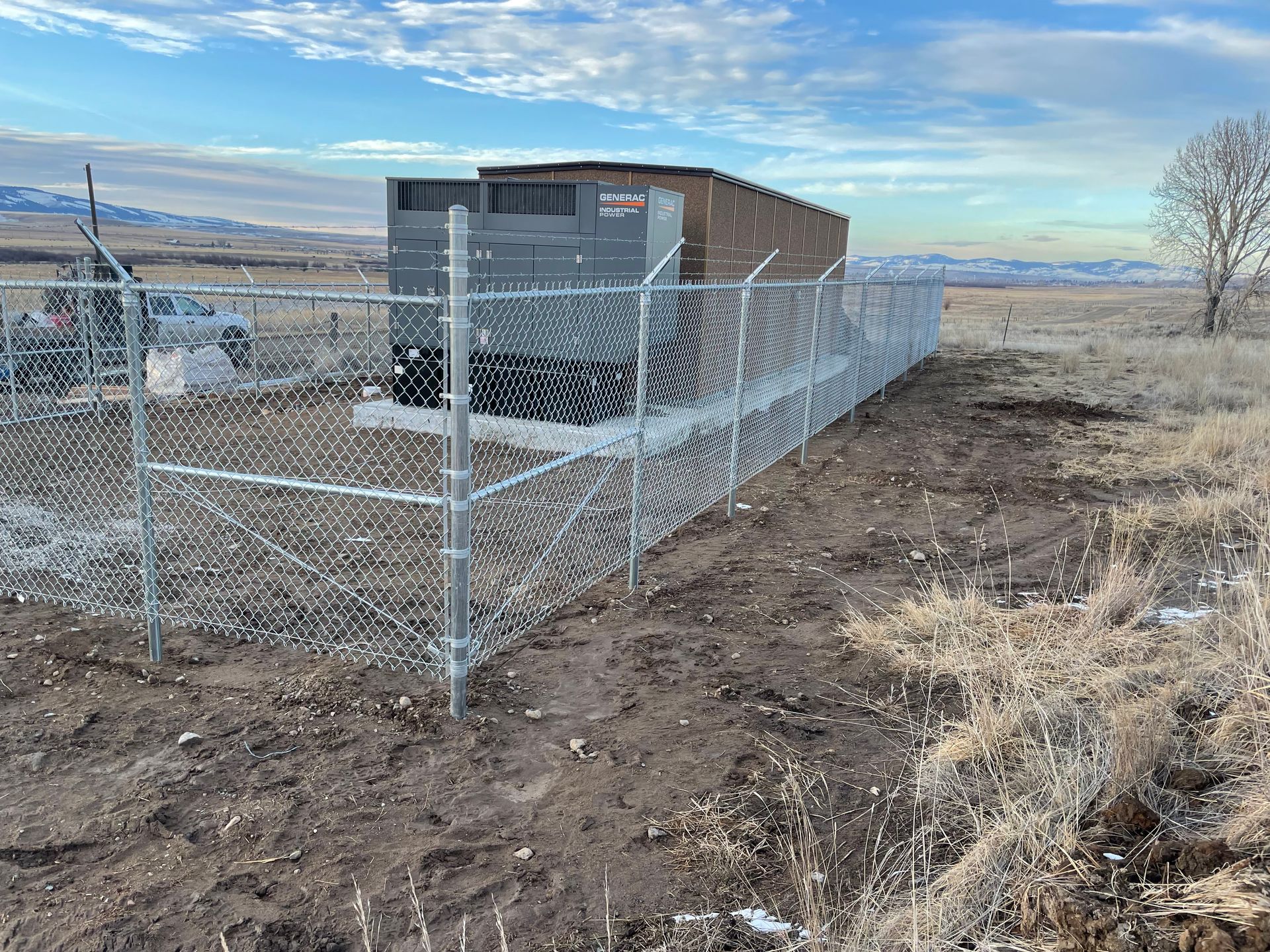 A chain link fence surrounds a building in a field.