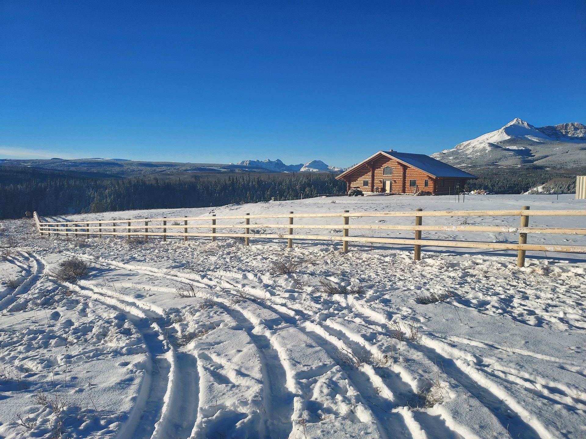 A snowy field with a fence and a house in the background