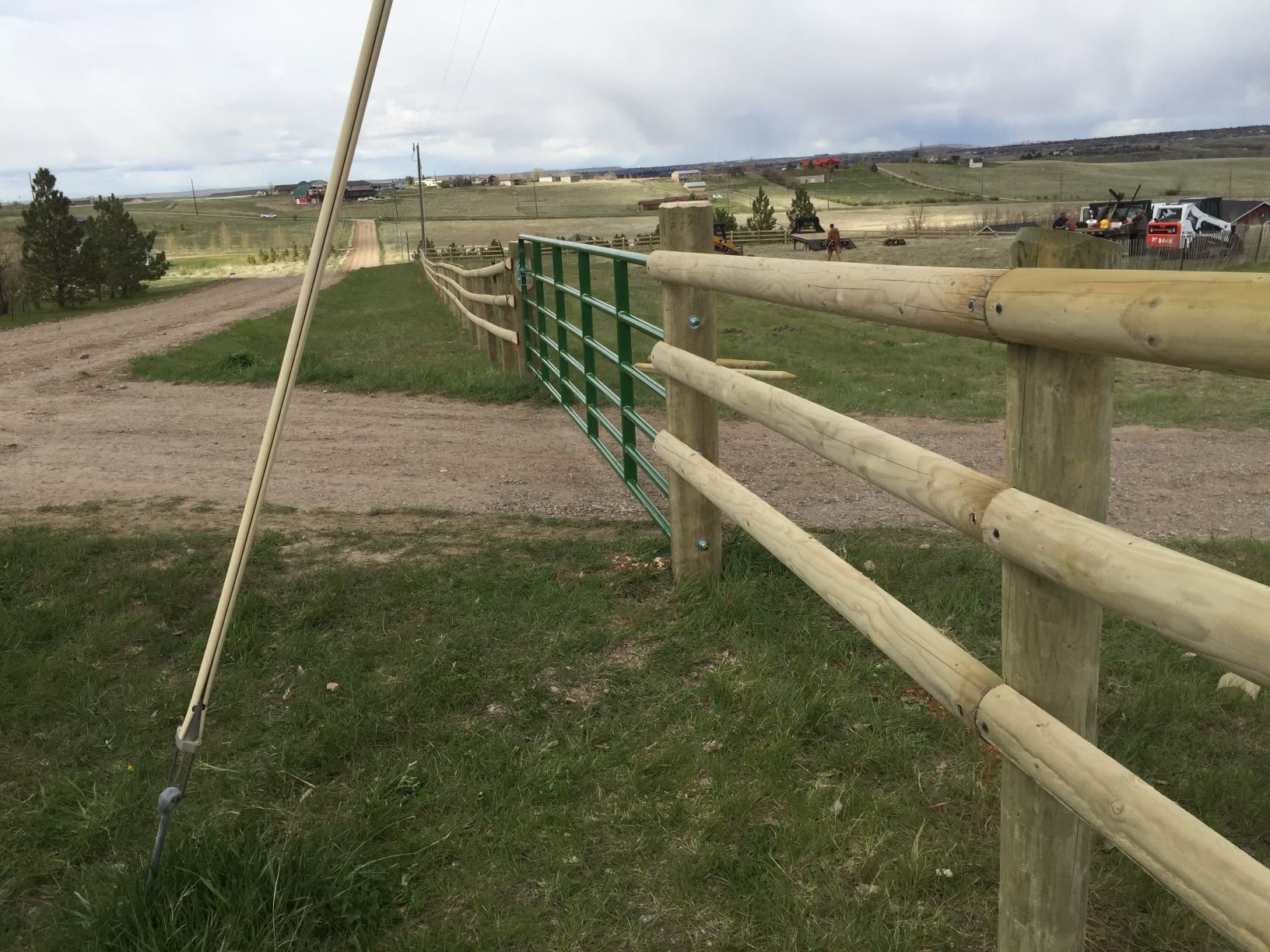 A wooden fence surrounds a dirt road in a field