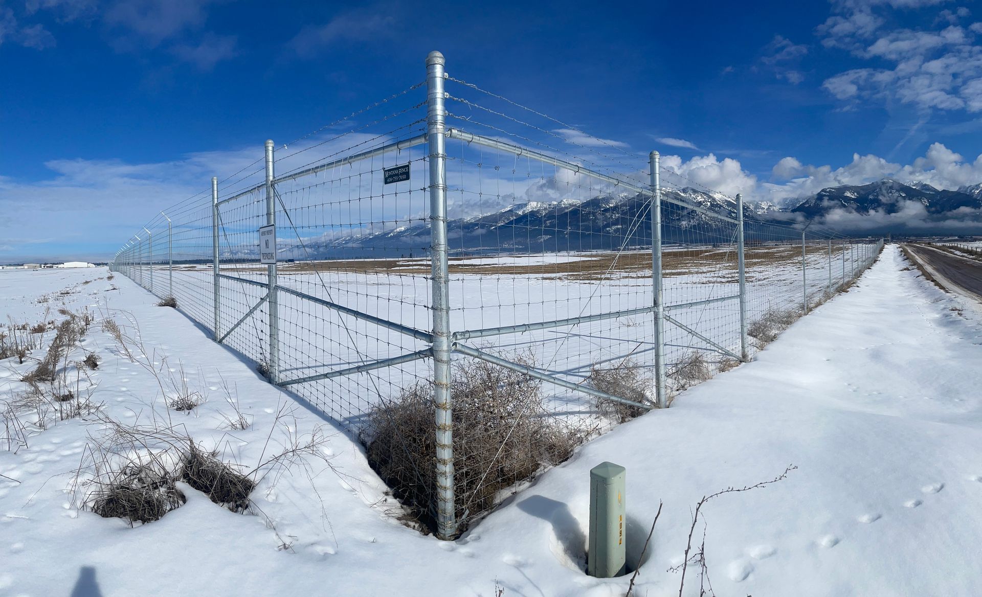A snowy field with a barbed wire fence in the foreground.