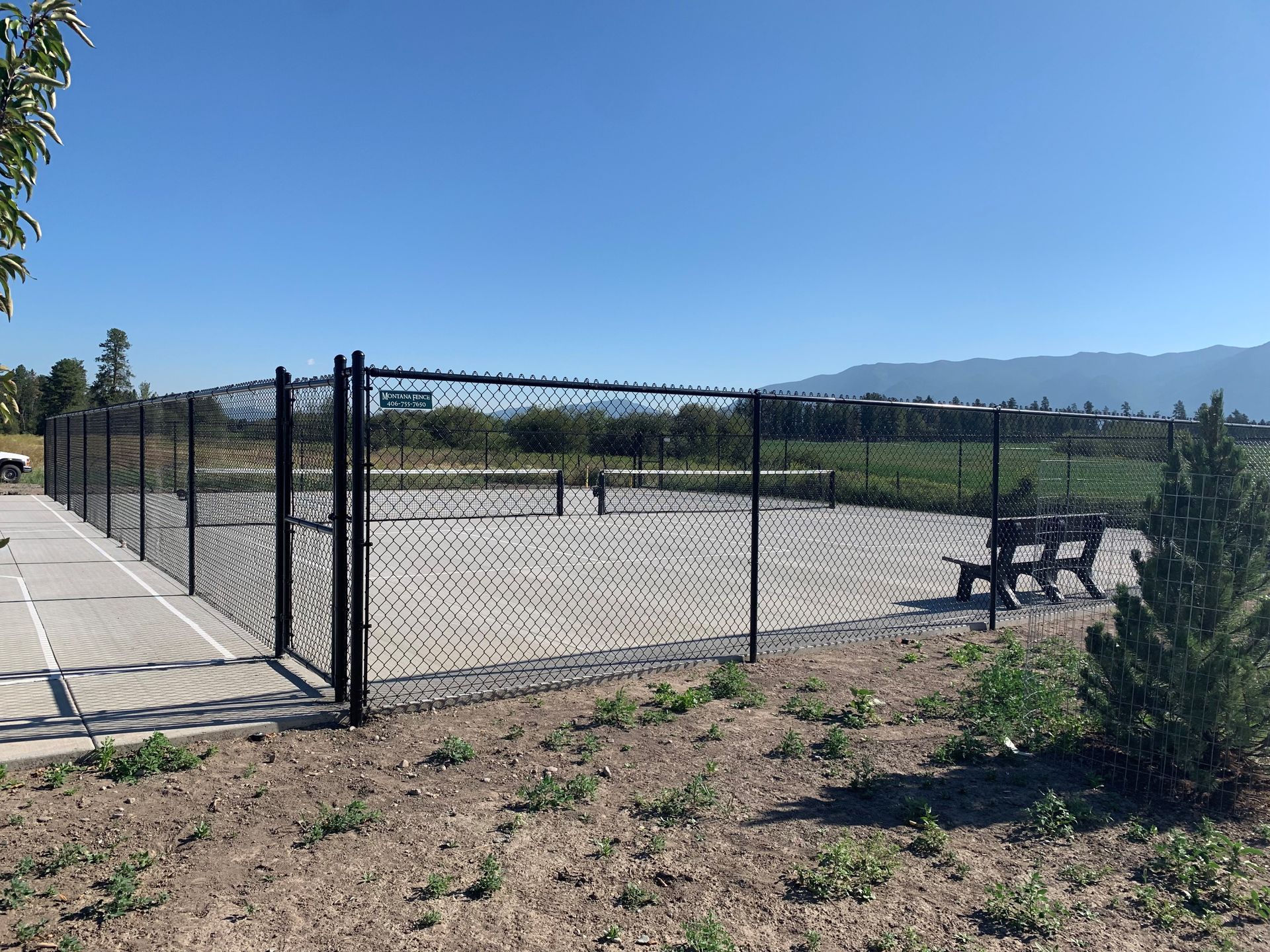 A dog park with a chain link fence and a bench.