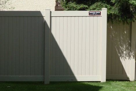 A white vinyl fence is sitting on top of a lush green lawn.