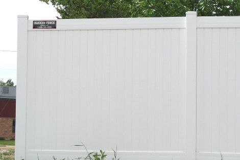 A white vinyl fence is sitting in the grass in front of a house.