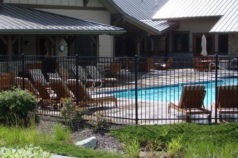 A large swimming pool is surrounded by a fence and chairs.