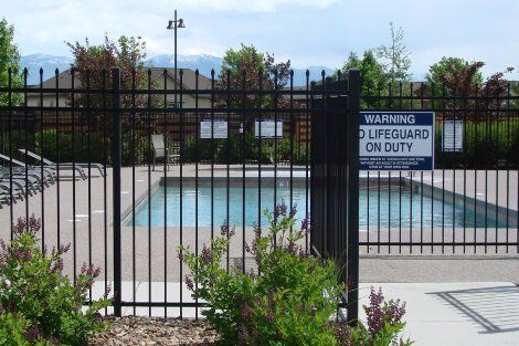 A lifeguard on duty sign is behind a fence
