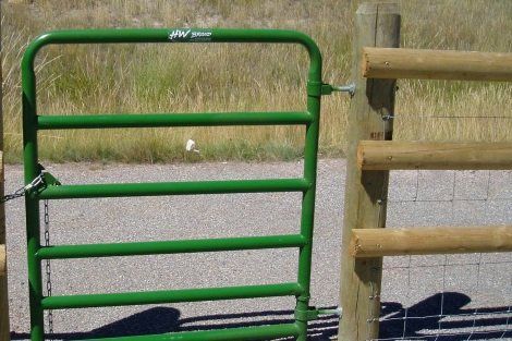 A green gate is sitting next to a wooden fence.
