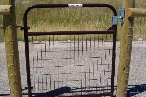 A fence with a gate and a shadow on the ground
