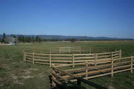 A wooden fence is in the middle of a grassy field.