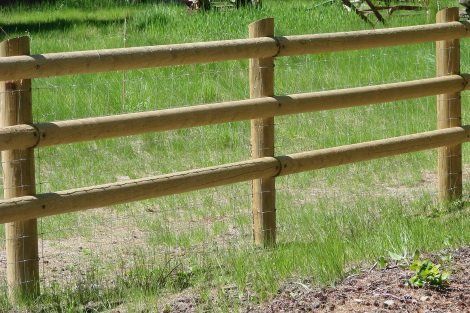 A wooden fence is in the middle of a grassy field.