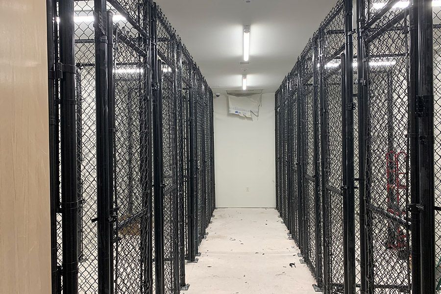 A long hallway with a row of fenced in lockers.