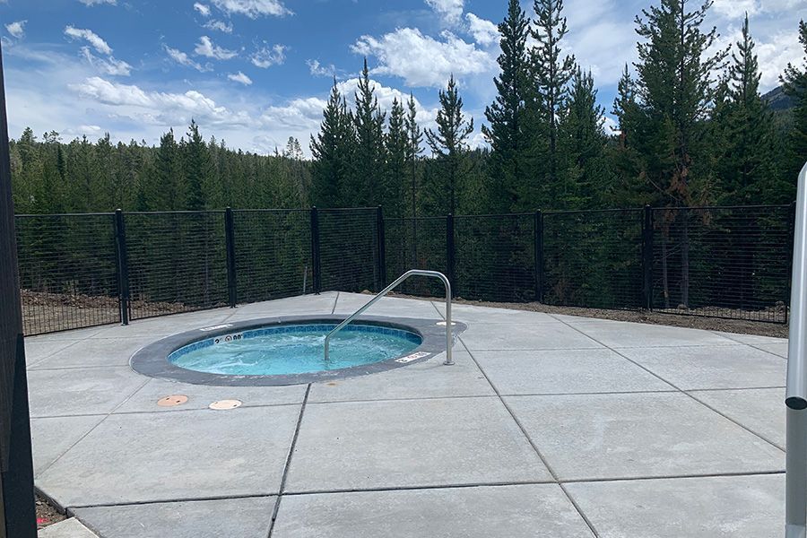 A hot tub is sitting on top of a concrete patio surrounded by trees.