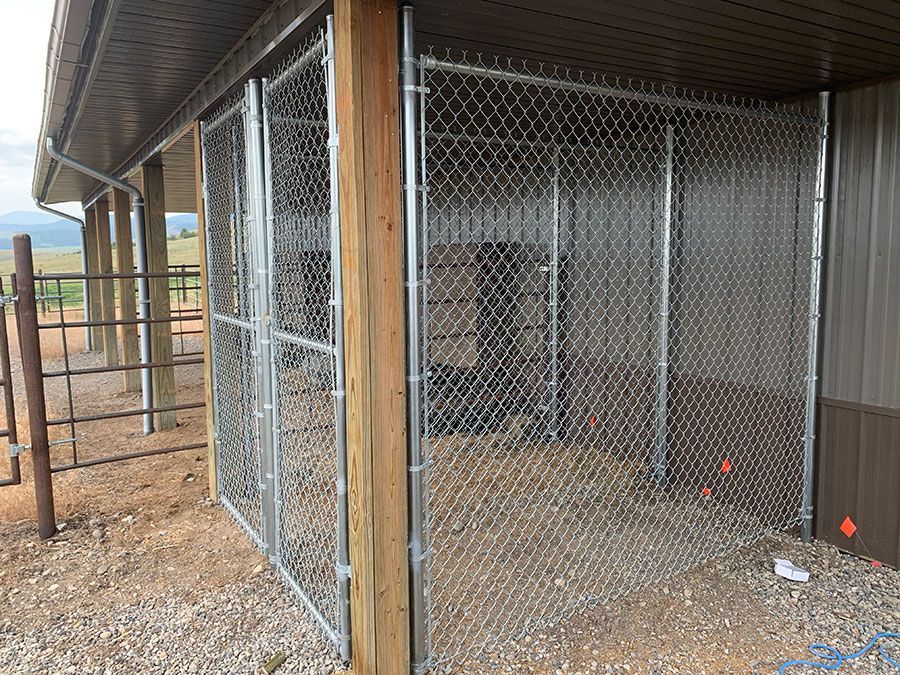 A chain link fence is surrounding a dog kennel.