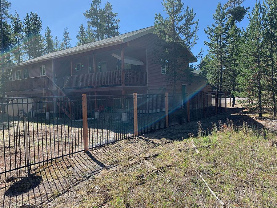 A large house with a fence around it is surrounded by trees.