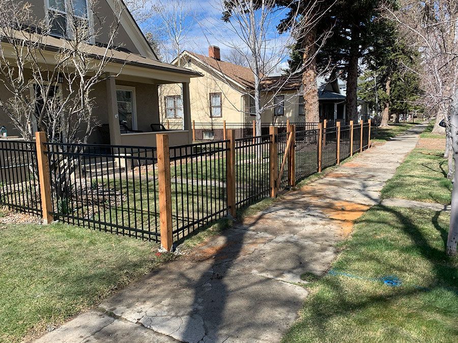 There is a fence along the sidewalk in front of a house.