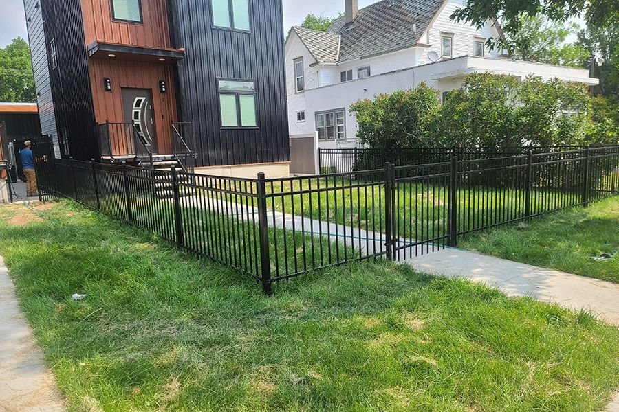 A black metal fence is in front of a house.