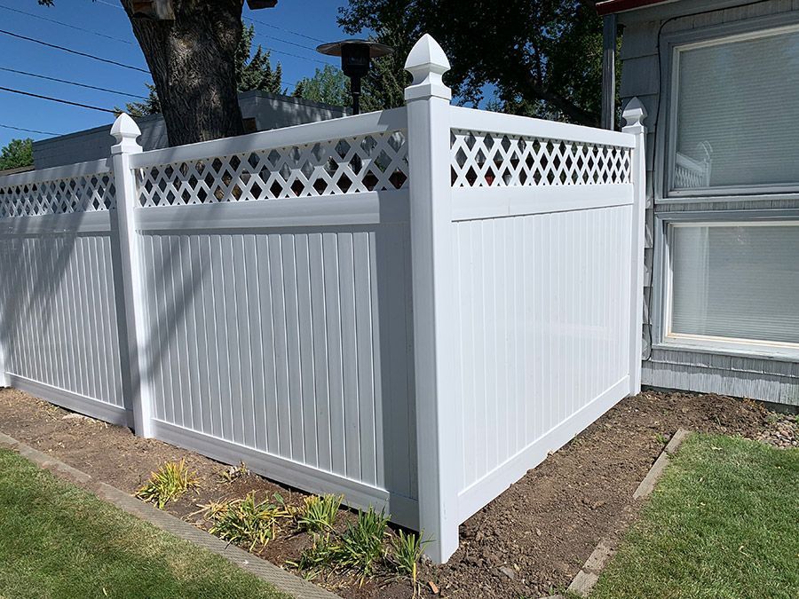 A white fence is sitting in front of a house.