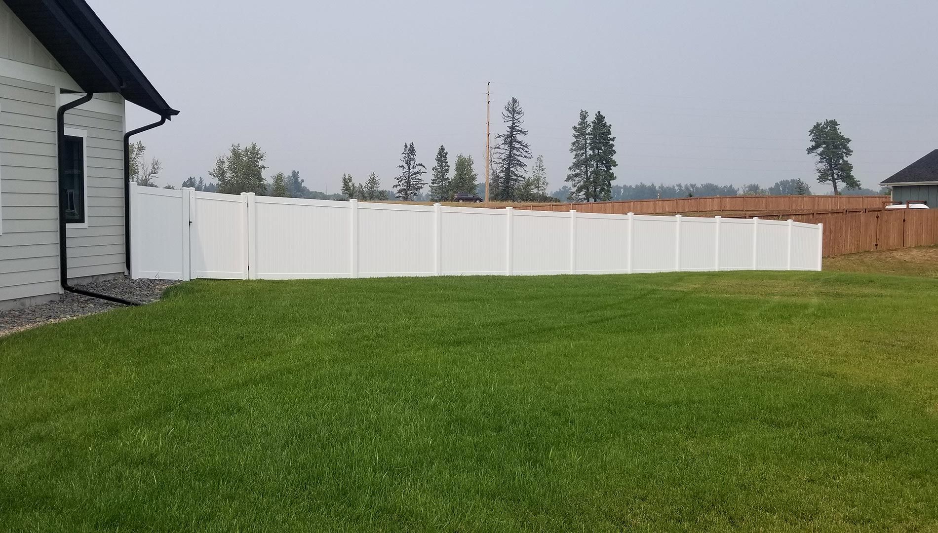 There is a white fence in the backyard of a house.
