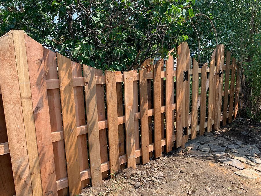 A wooden fence is sitting on top of a dirt path.