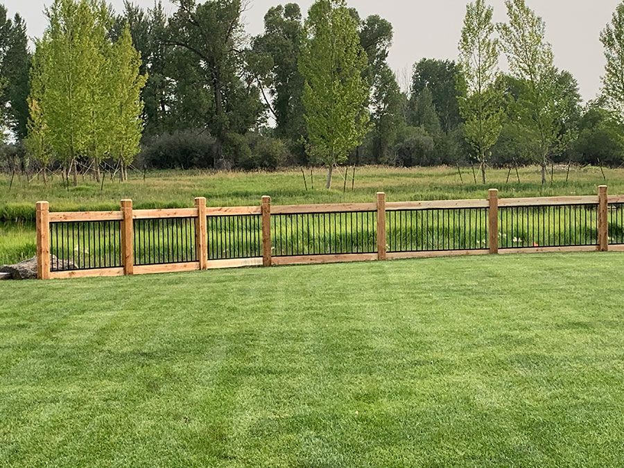 A wooden fence surrounds a lush green field.