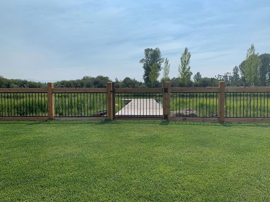 A wooden fence surrounds a lush green field.