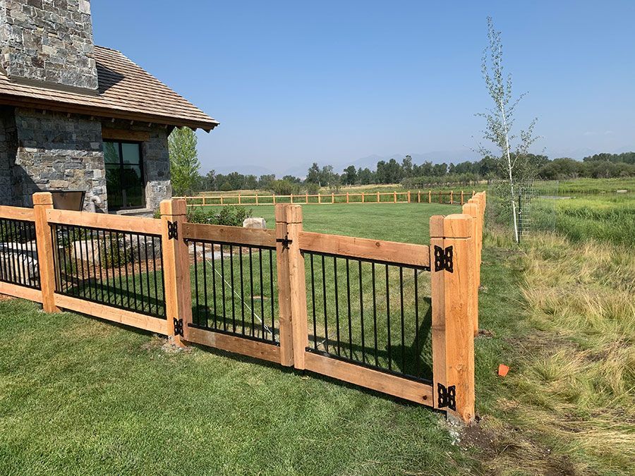 A wooden fence with black railings is in front of a house.