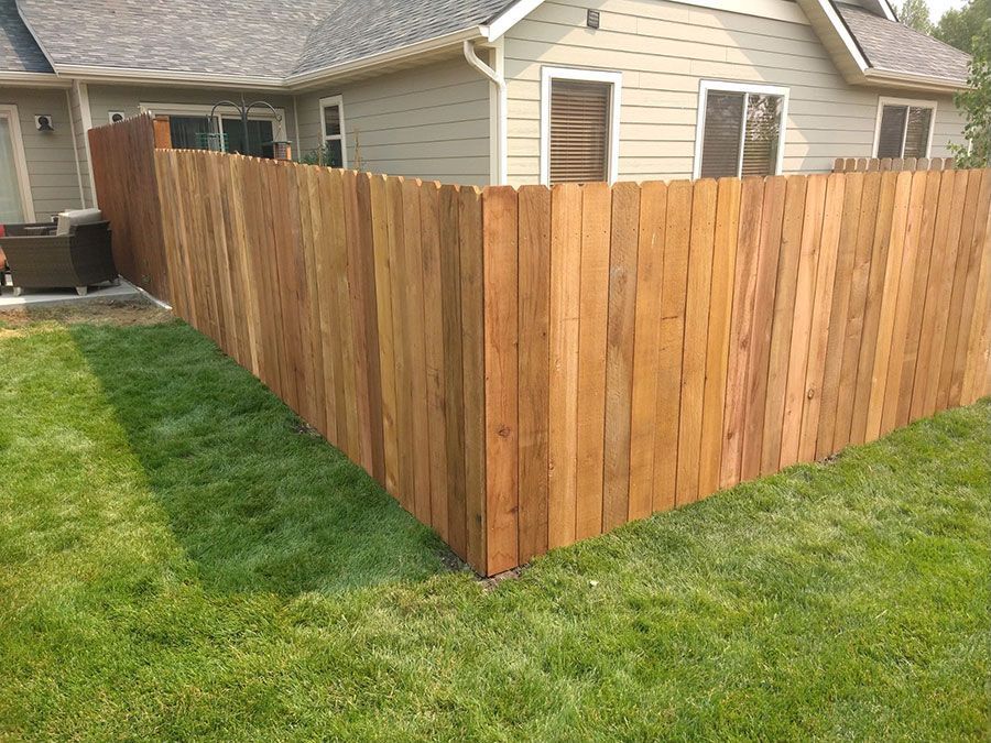 A wooden fence is in the backyard of a house.