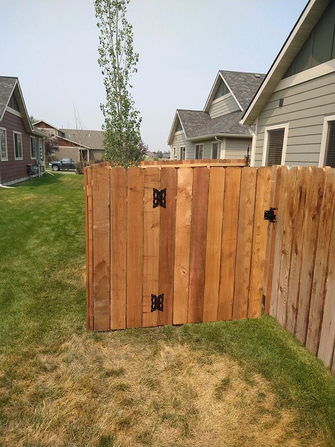 A wooden fence with a gate in the backyard of a house.