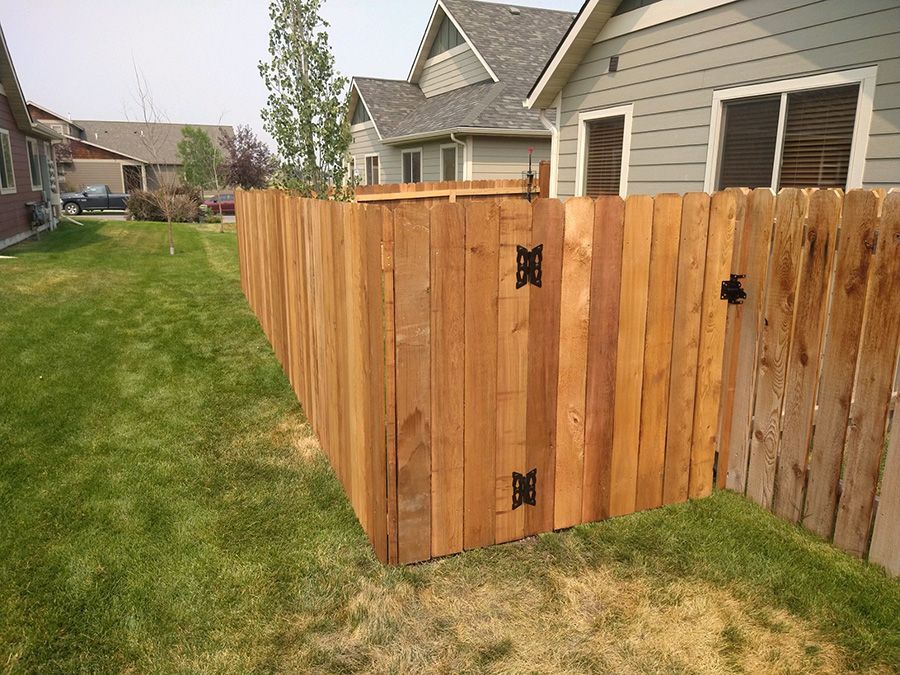 A wooden fence is in the backyard of a house.