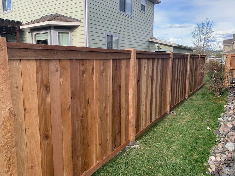 A wooden fence is sitting in the grass in front of a house.