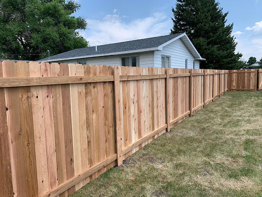 A wooden fence is in the backyard of a house.