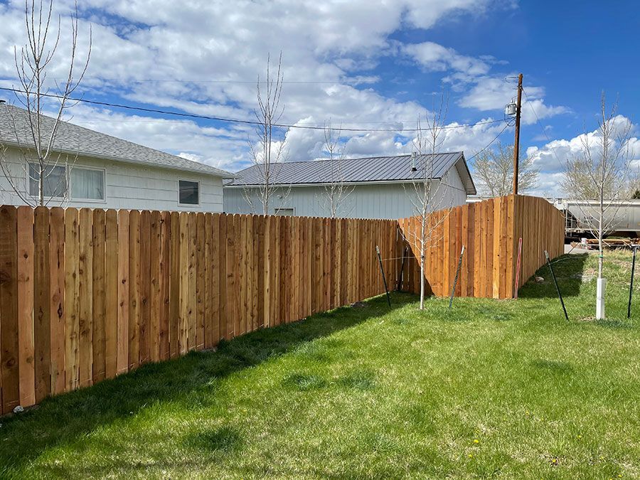 A wooden fence is in the backyard of a house.