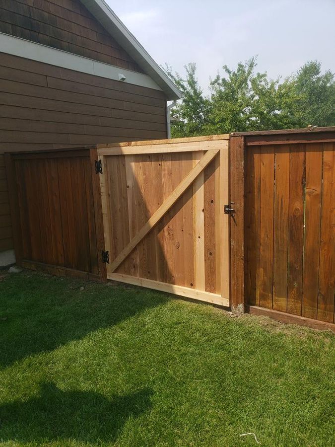 A wooden fence with a gate in the backyard of a house.