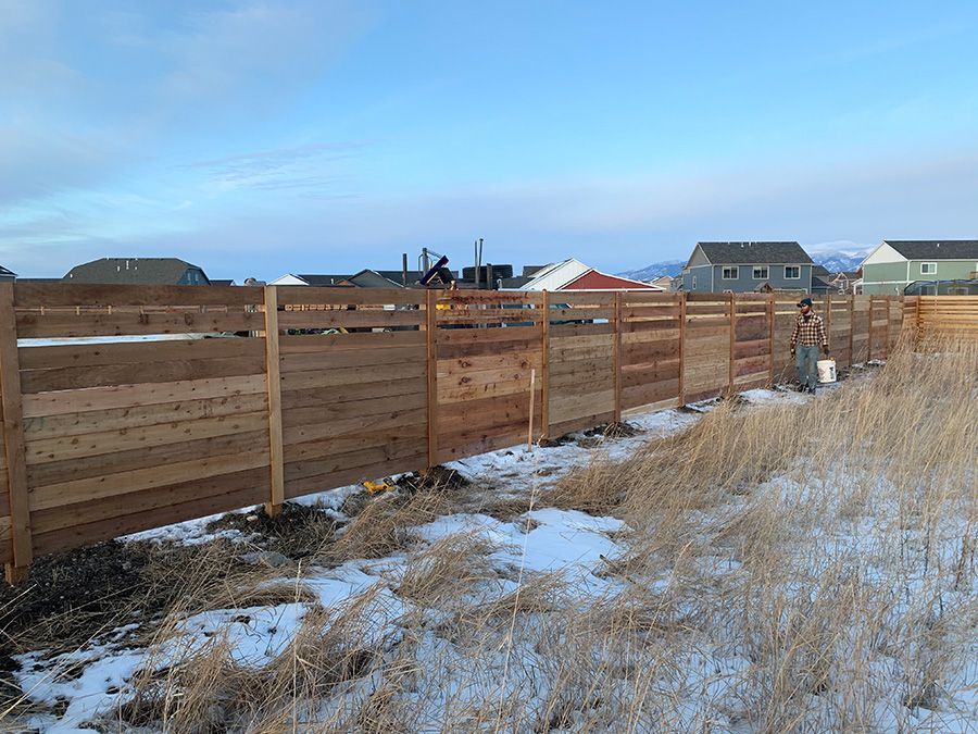 A wooden fence is being built in a snowy field.