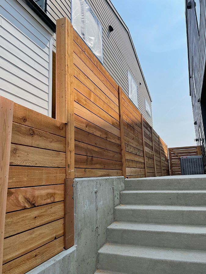 A wooden fence surrounds a set of stairs leading up to a house.