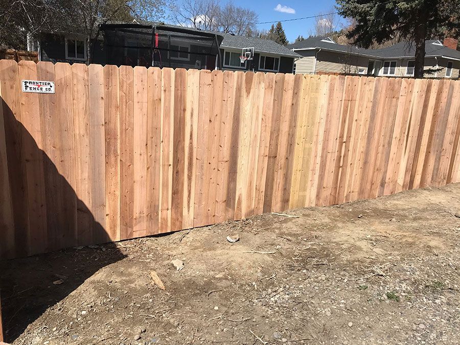 A wooden fence is sitting in the middle of a dirt field.