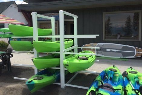 A bunch of green kayaks are stacked on top of each other on a rack.