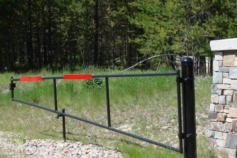 A black gate with a red stripe on it is sitting next to a stone pillar.