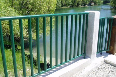 A green railing overlooking a body of water