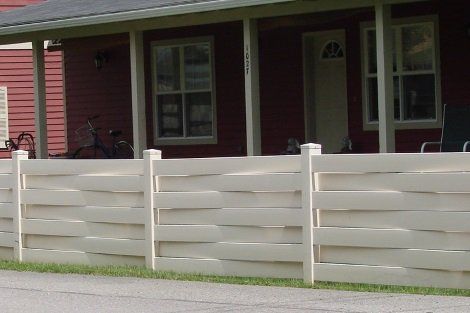 A white fence is in front of a red house